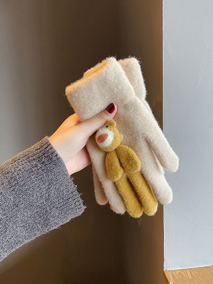 Folded beige gloves with a mustard animal applique held in one hand