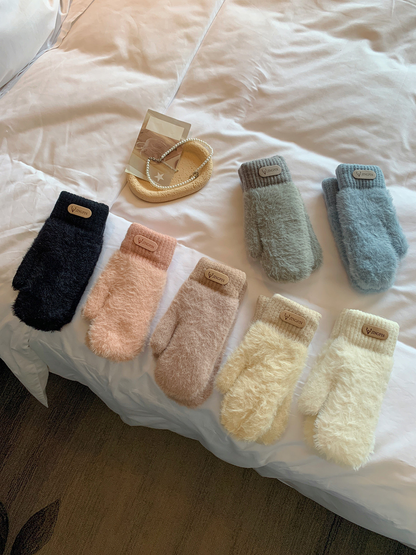 Seven fuzzy mitten color options arranged on a bed