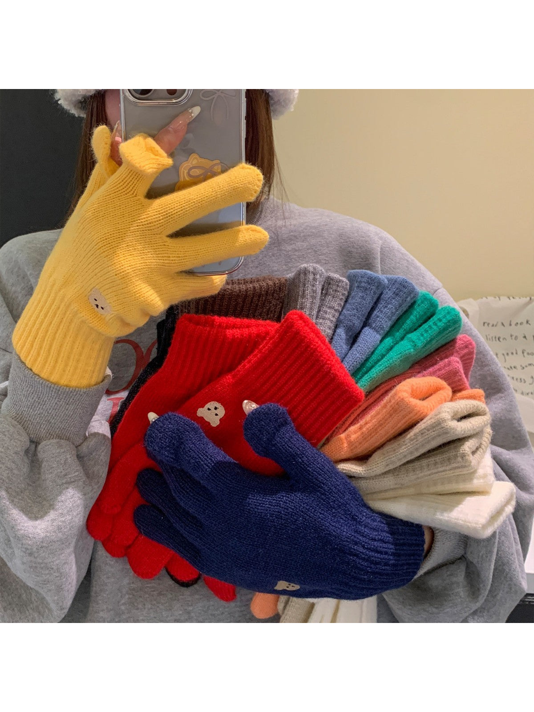Knit gloves in assorted colors held and worn in a mirror setting