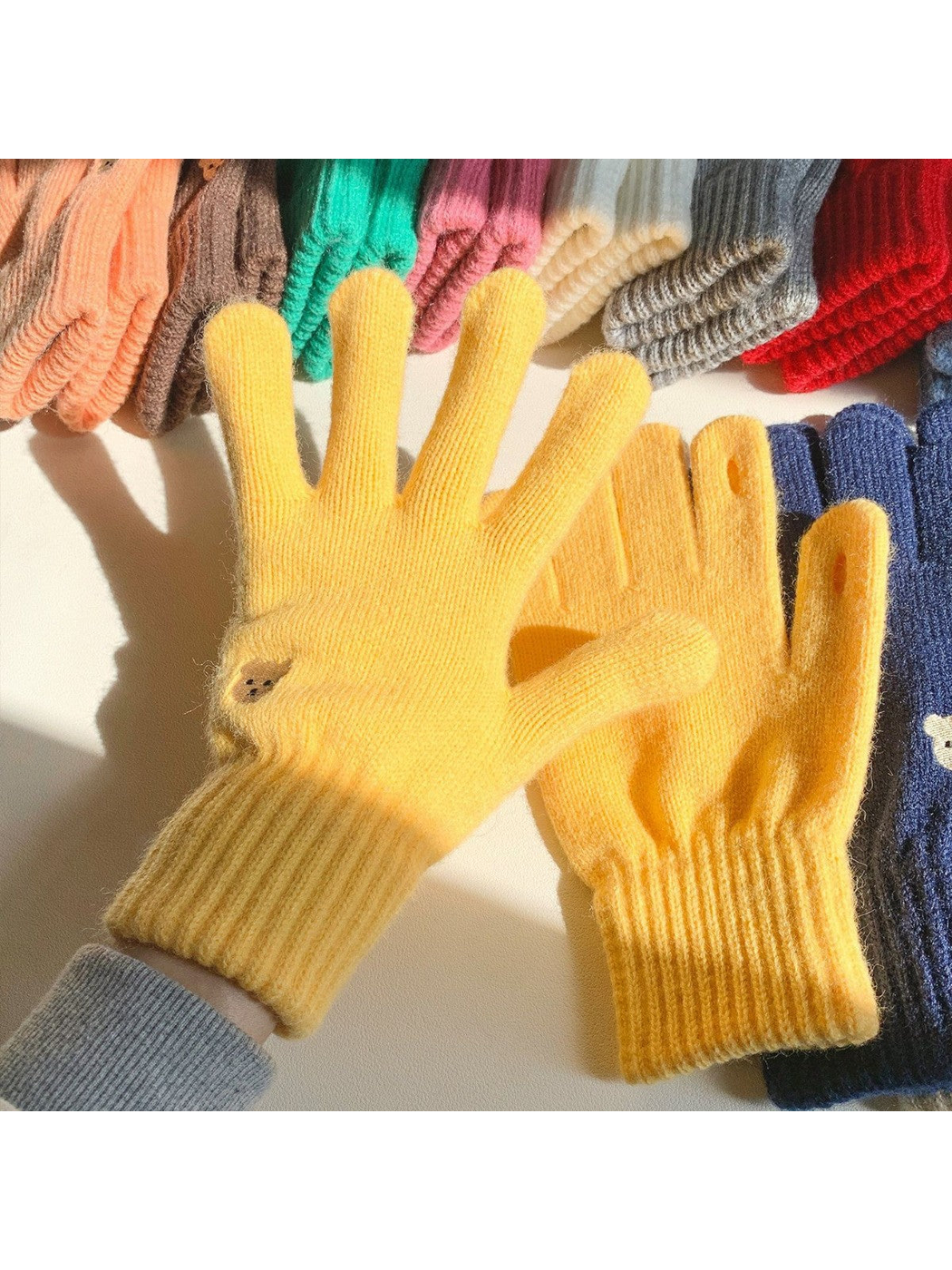 Yellow knit gloves displayed with assorted color options in sunlight