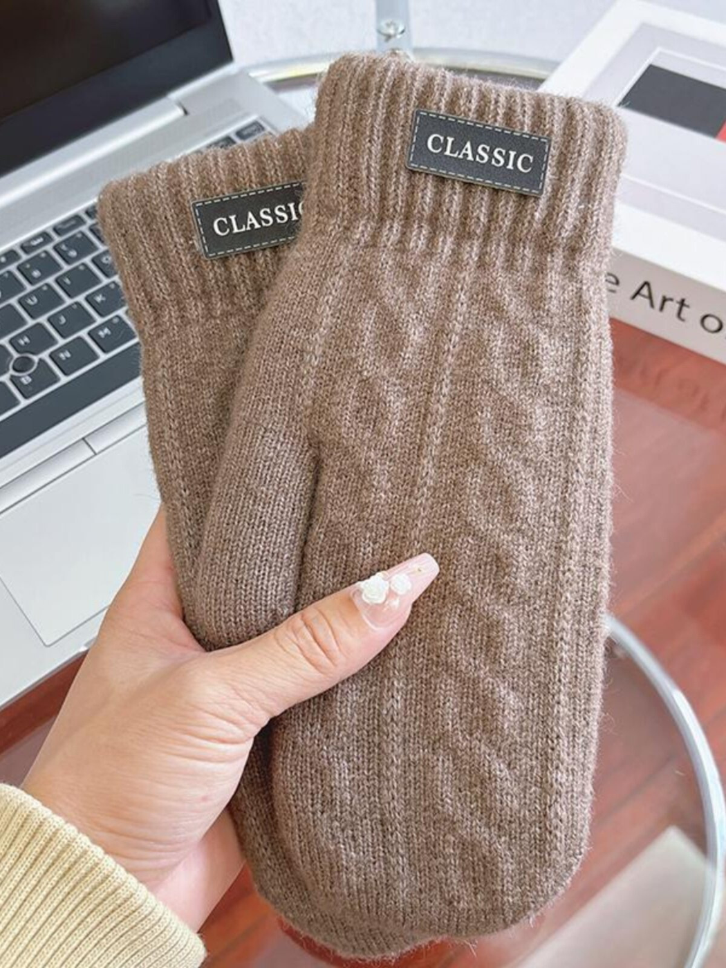 Brown knit-look mittens with ribbed cuffs and label patches, handheld view