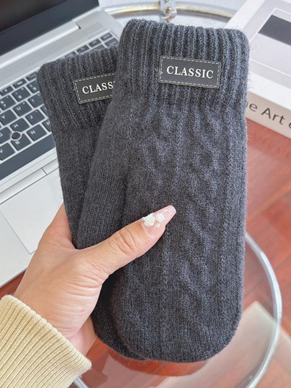 Dark gray knit-look mittens with ribbed cuffs and label patches, handheld view