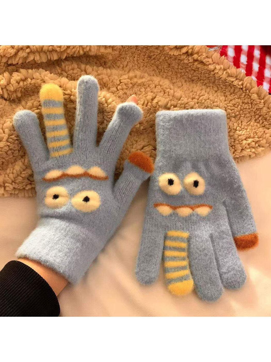 Light blue fuzzy cartoon face gloves with raised eyes and striped finger details