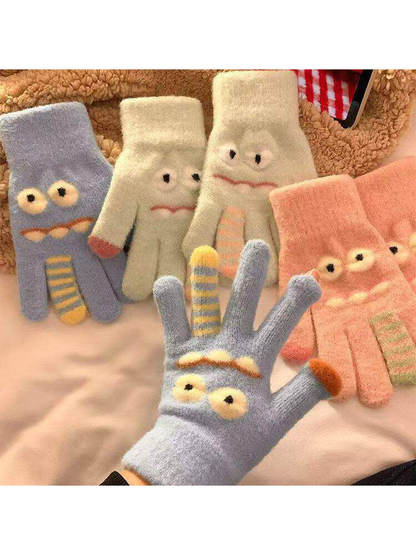 Cartoon face gloves in multiple colors arranged together with a light blue glove worn