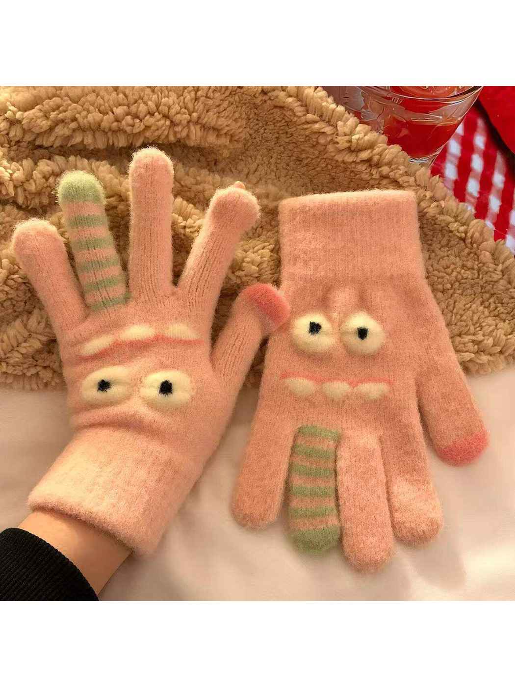 Blush pink fuzzy cartoon face gloves with raised eyes and striped finger details
