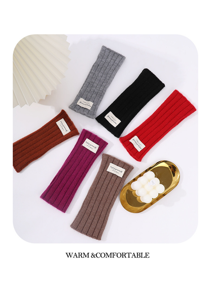 Six colors of ribbed fingerless gloves arranged in a flat lay