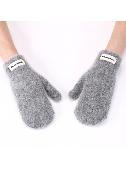 Dark gray fuzzy mittens worn against a white background
