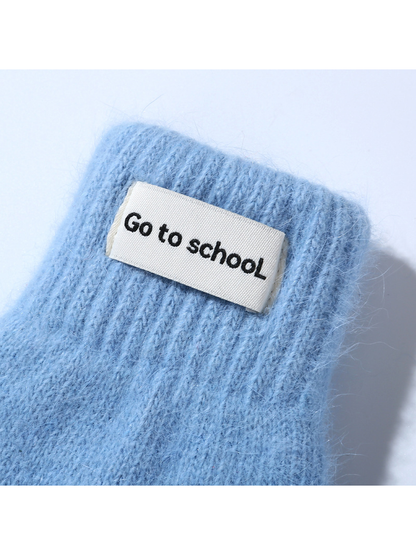 Close-up of a light blue mitten's ribbed cuff and rectangular label
