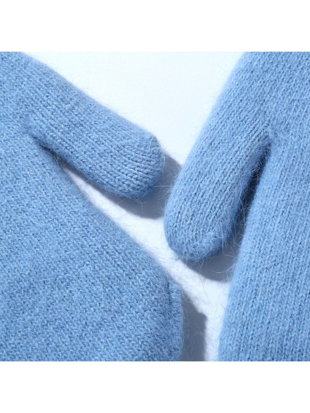 Close-up of the light blue mittens' fuzzy knit texture and thumb seams