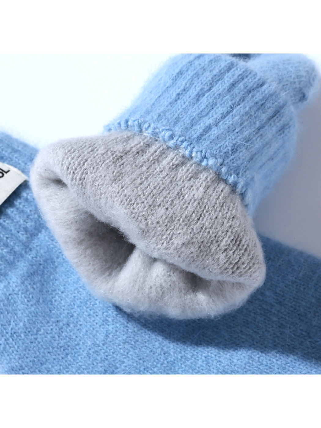 Close-up of a light blue mitten cuff with contrasting light gray interior