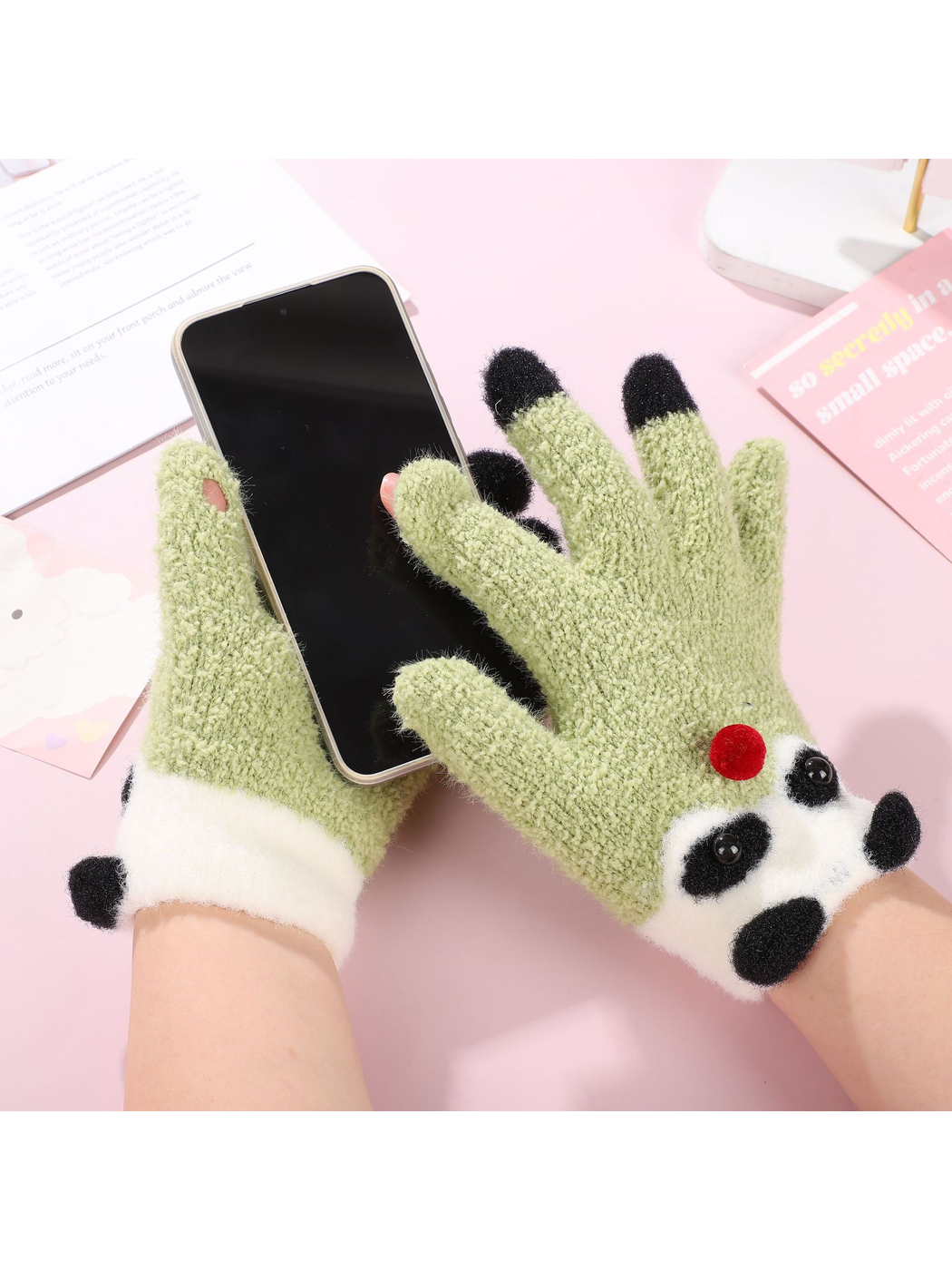 Light green panda motif gloves holding a smartphone with two fingertips exposed
