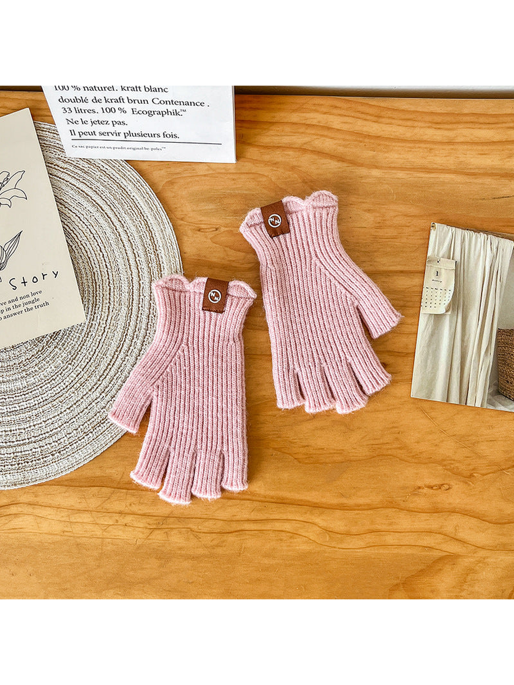 Pair of light pink ribbed fingerless gloves laid flat
