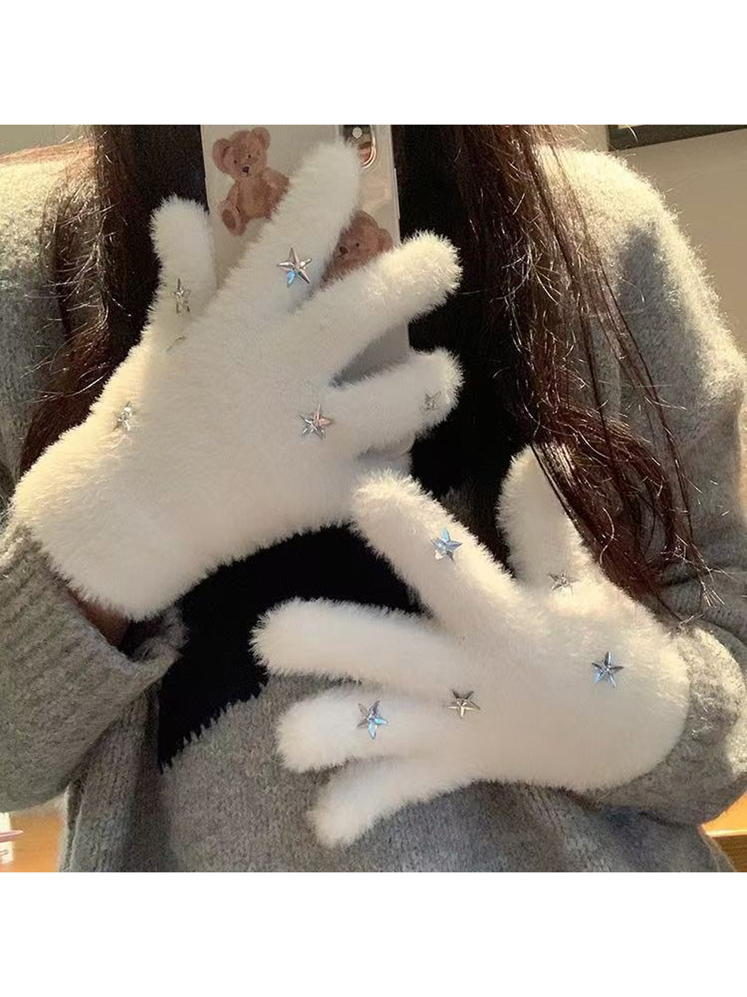 White fuzzy star gloves worn while holding a phone
