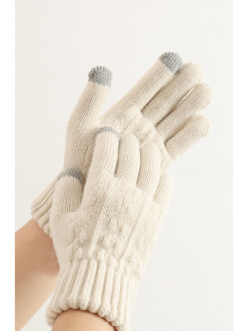 Beige cable-knit gloves worn with the palms and contrasting fingertips visible