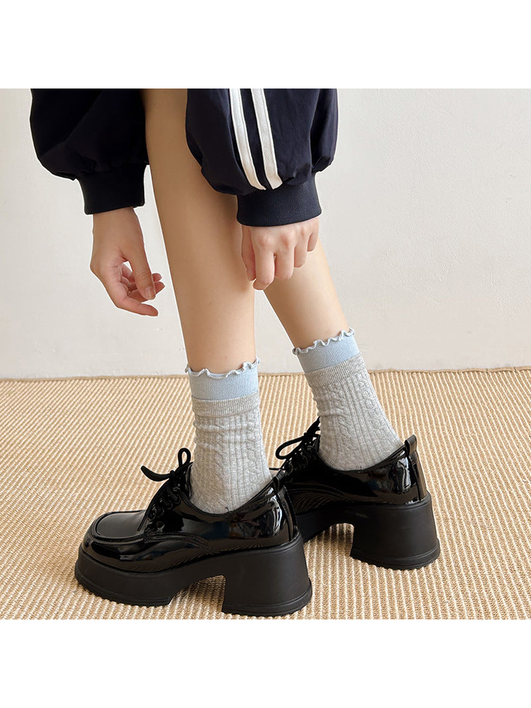 Light gray crew socks with blue ruffled cuffs worn with black platform shoes