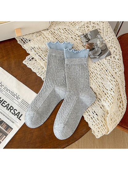 Light gray crew socks with blue ruffled cuffs and ribbed geometric texture