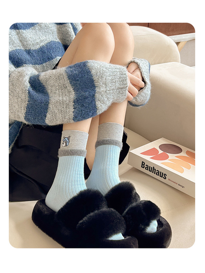 Light blue embroidered crew socks styled with black plush slippers