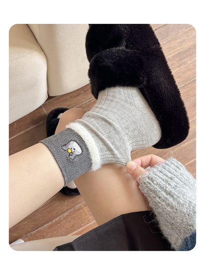 Close-up of gray ribbed sock and embroidered cuff with fuzzy trim