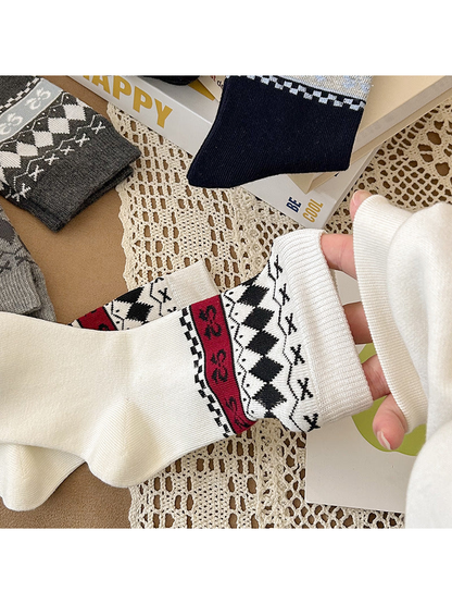 Close-up of a white patterned crew sock cuff being stretched by hand