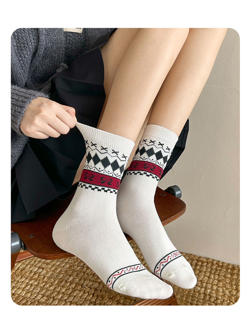 White patterned crew socks worn while one ribbed cuff is stretched by hand