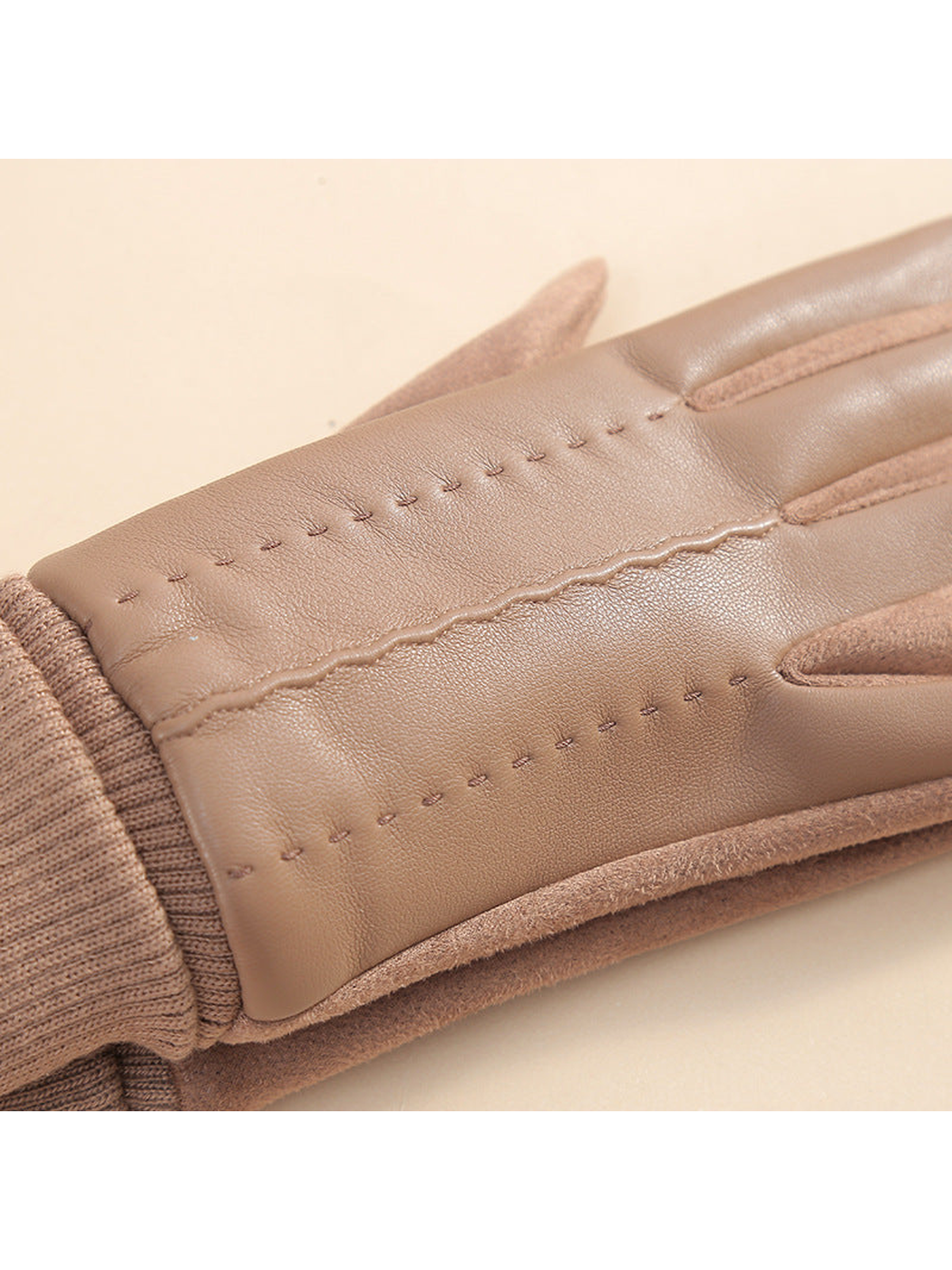 Close-up of decorative stitching and the wavy center seam on a camel glove