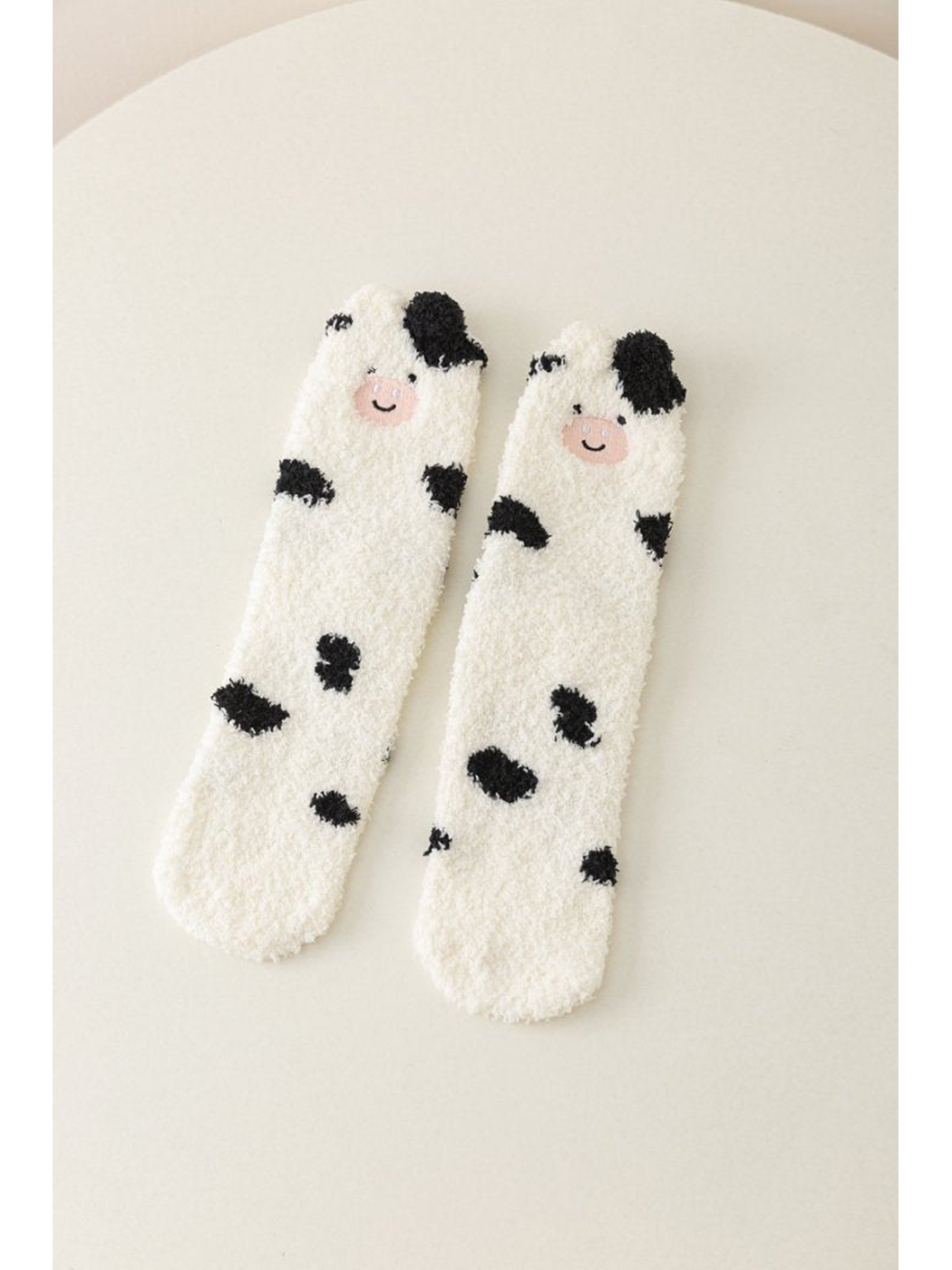 White fuzzy crew socks with cow faces and black spots
