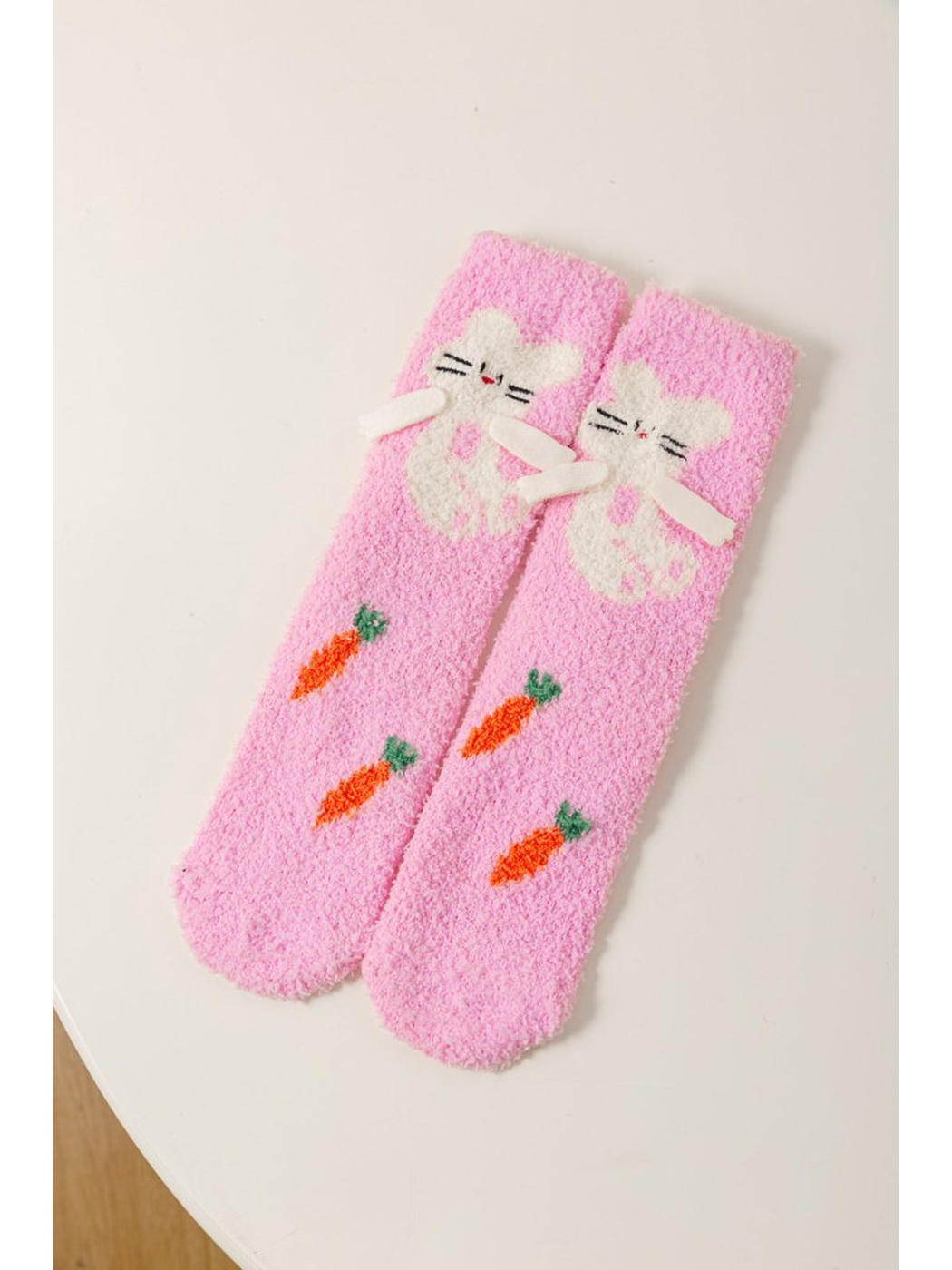 Pink fuzzy crew socks with a white cat and carrot motifs
