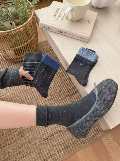 Floral crew sock worn with a fuzzy gray flat while three additional sock styles are held nearby