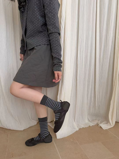 Dark gray crew socks with narrow blue and white horizontal stripes, worn view