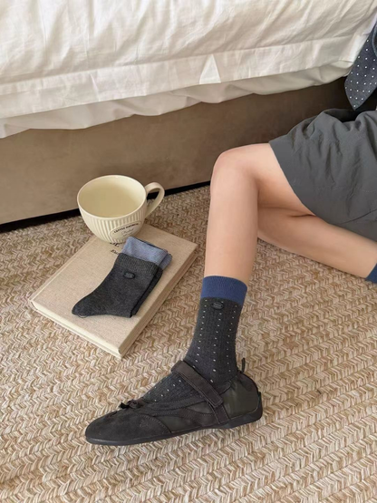 Dotted dark gray crew sock with a blue cuff worn with a dark strap shoe
