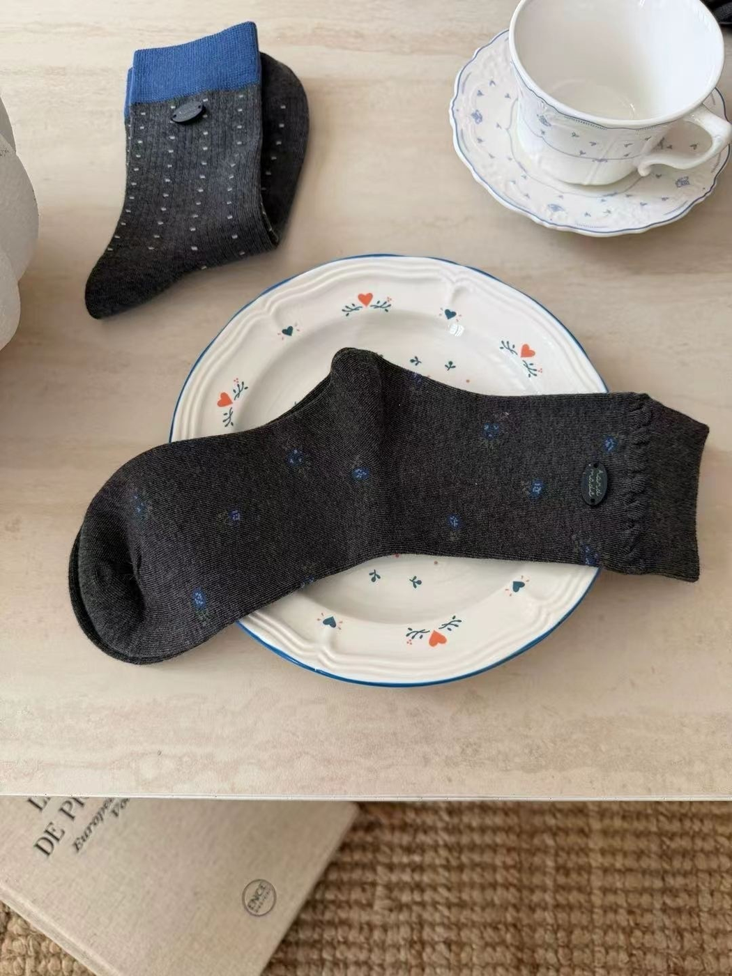 Dark gray floral crew sock displayed with a blue-cuffed dotted style
