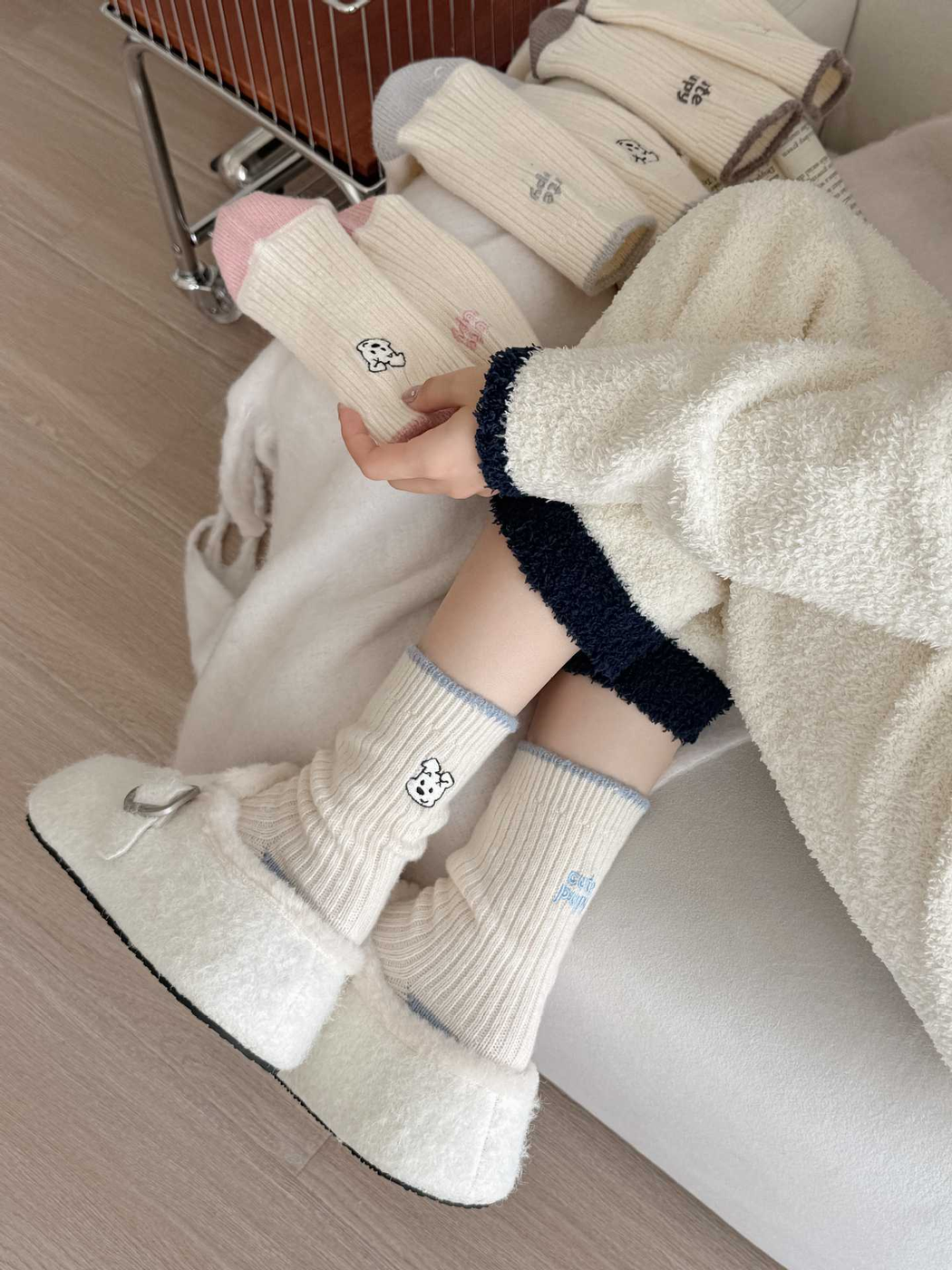 Blue puppy-motif crew socks worn with plush shoes while pink socks are held