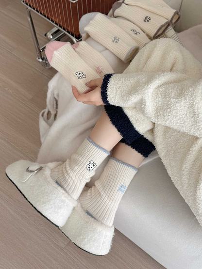 Blue puppy-motif crew socks worn with plush shoes while pink socks are held