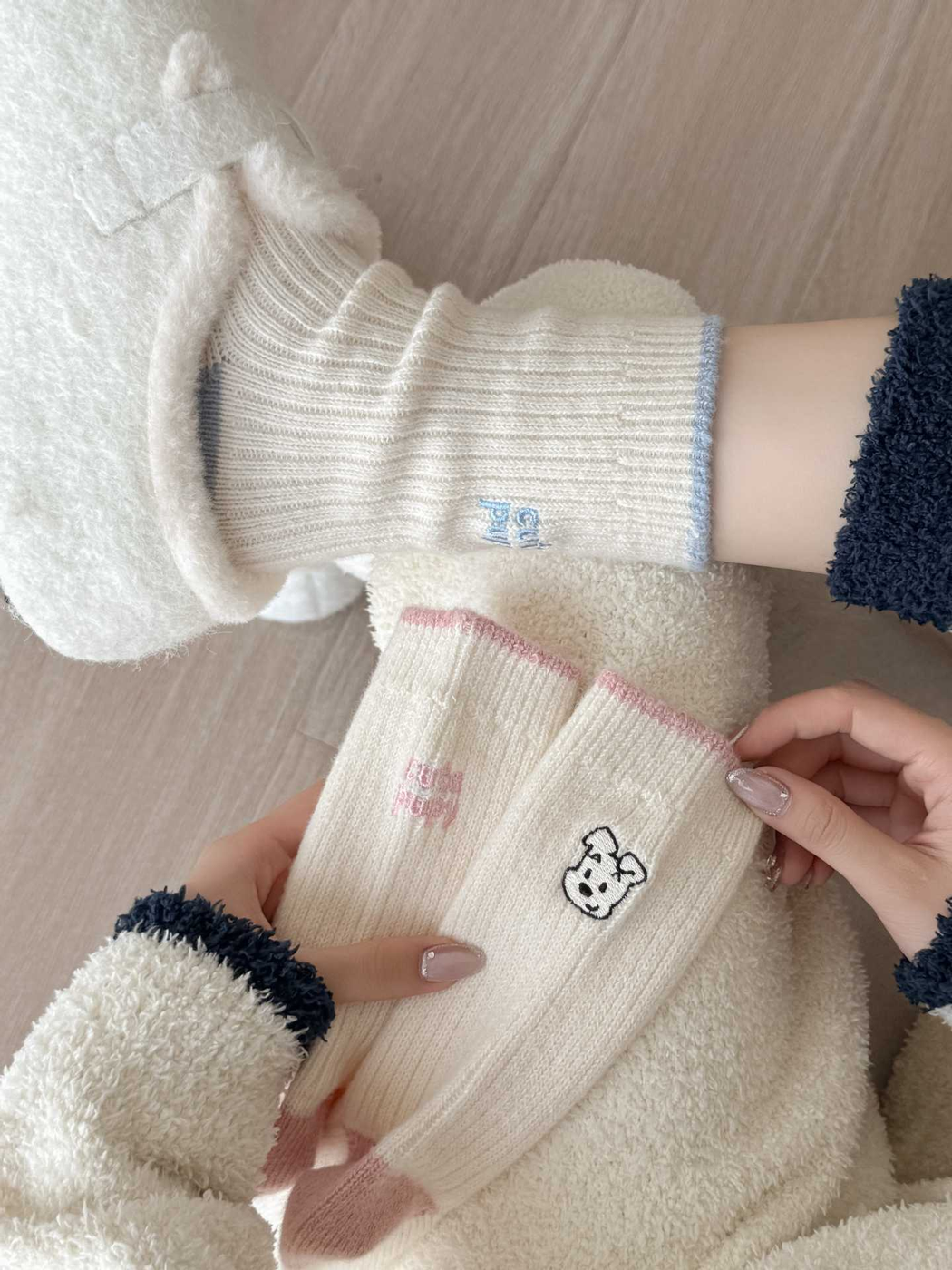 Pink puppy-motif socks held beside blue socks worn with plush shoes
