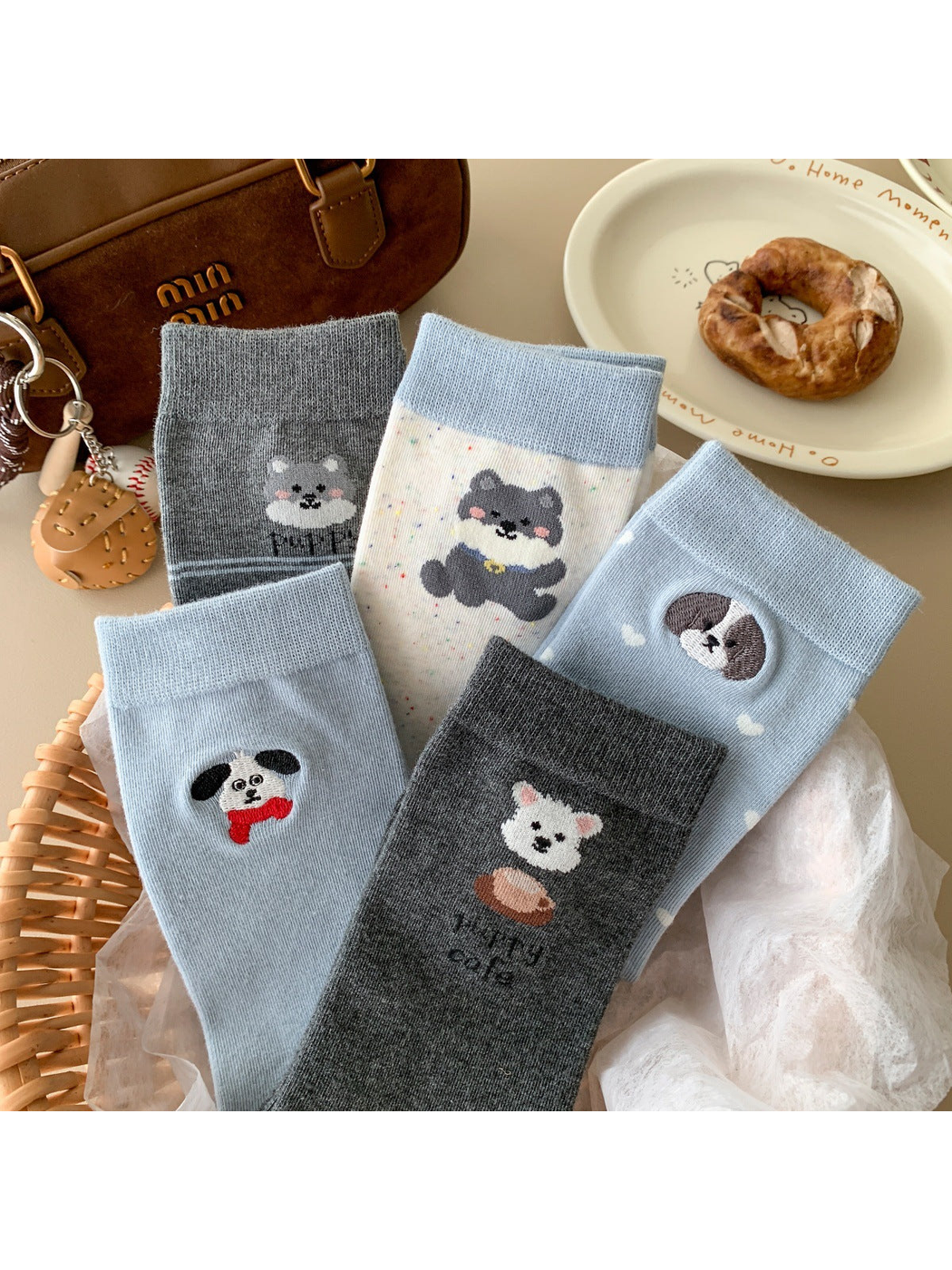 Five animal motif crew sock styles arranged with neutral accessories