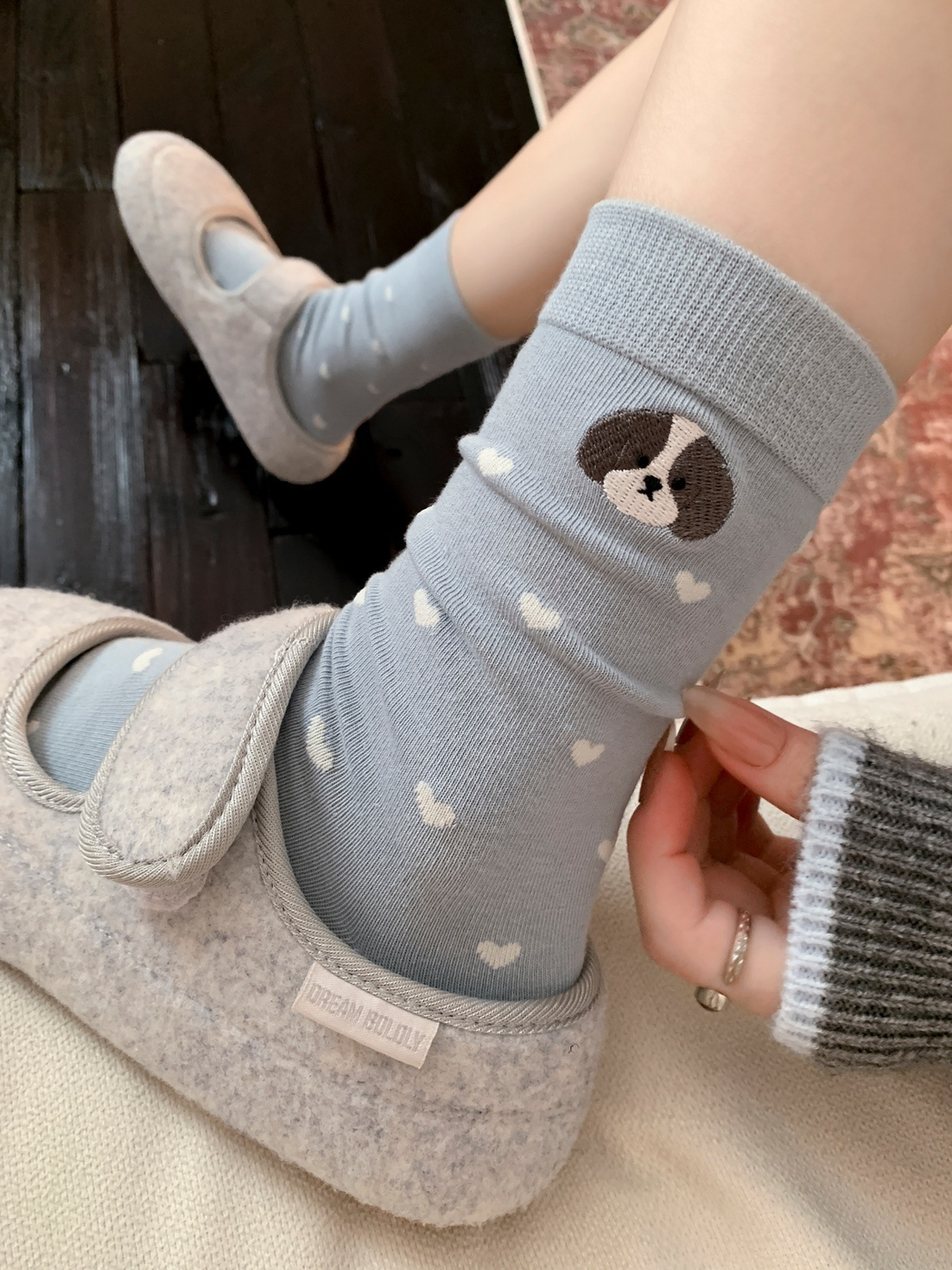 Light blue heart pattern dog crew socks worn with gray slippers
