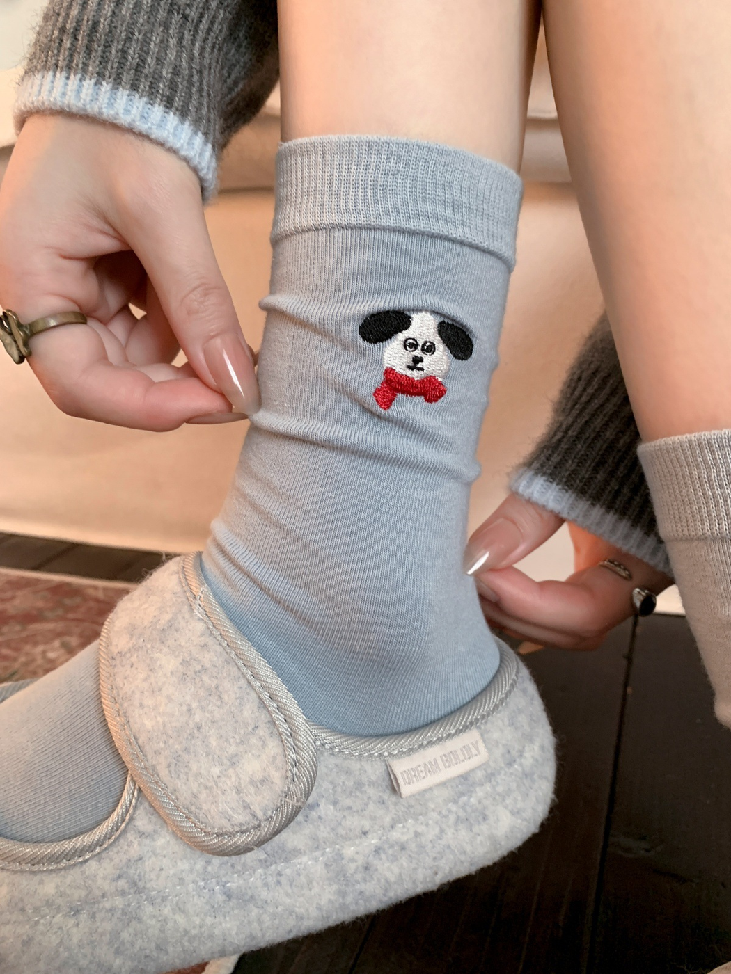 Light blue dog and red bow tie crew sock worn with a gray slipper