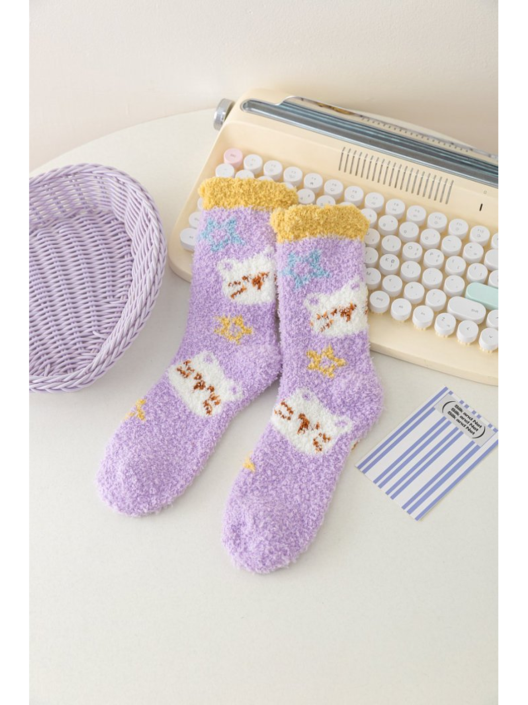 Light purple fuzzy socks with cat motifs and yellow cuffs
