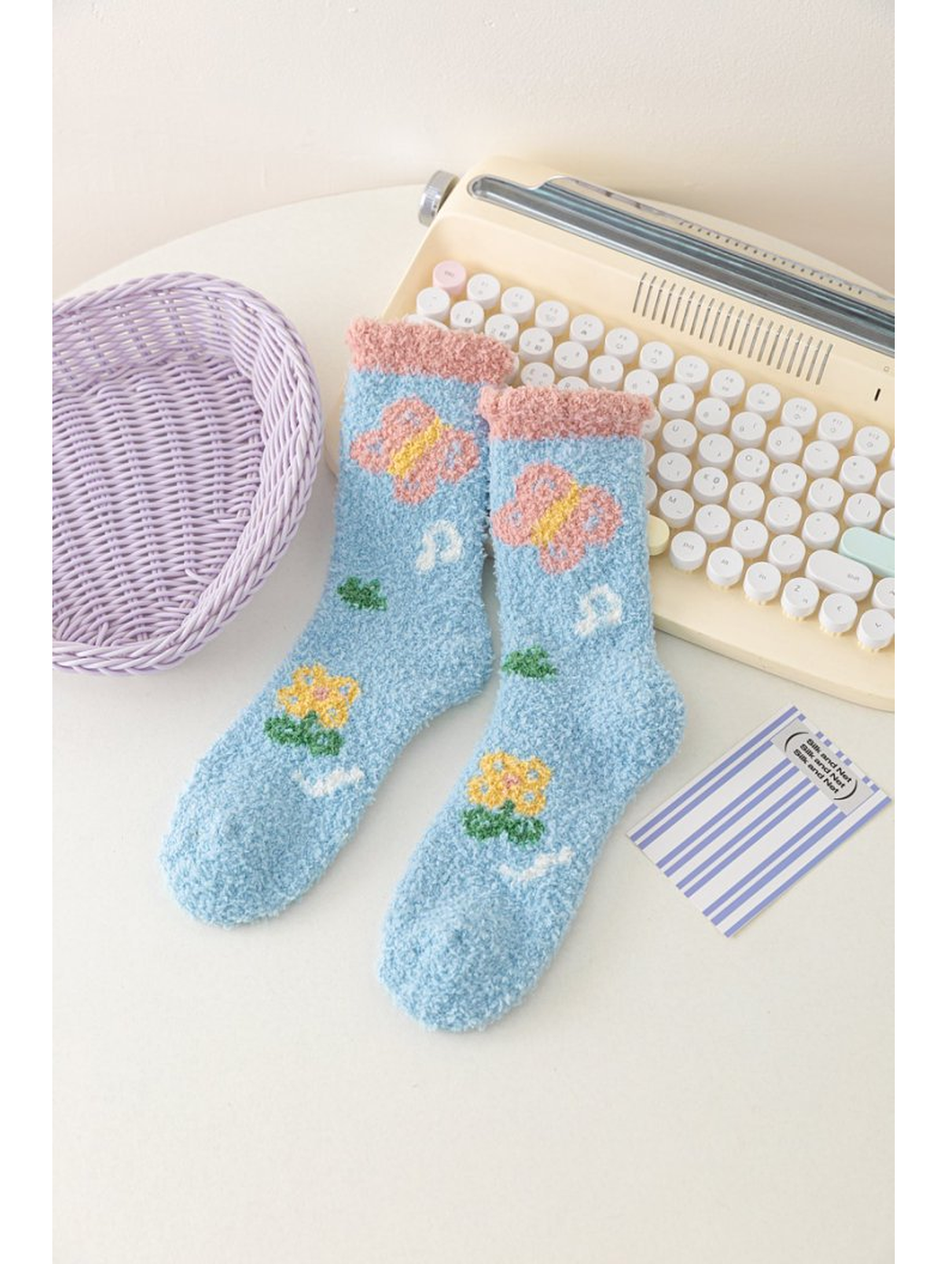 Light blue fuzzy socks with butterfly and flower motifs