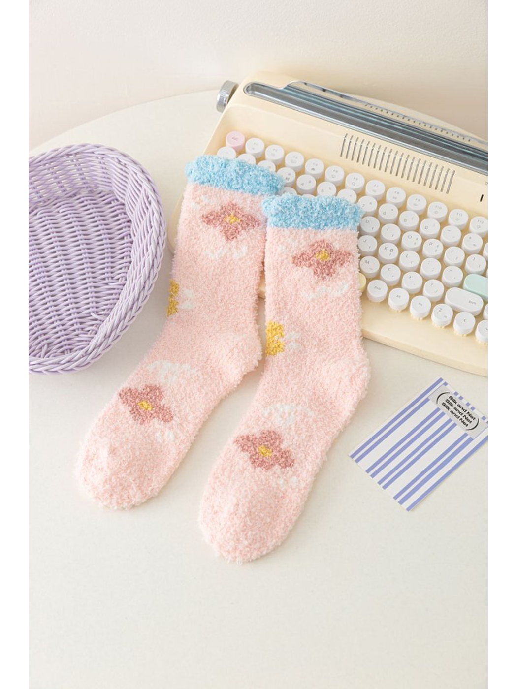 Light pink fuzzy socks with flower motifs and blue cuffs