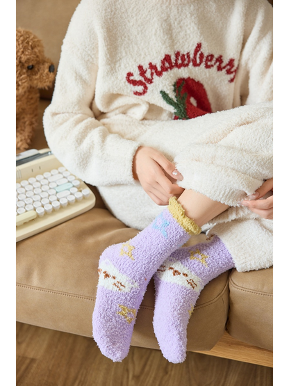 Light purple fuzzy cat-pattern socks worn while seated on a sofa