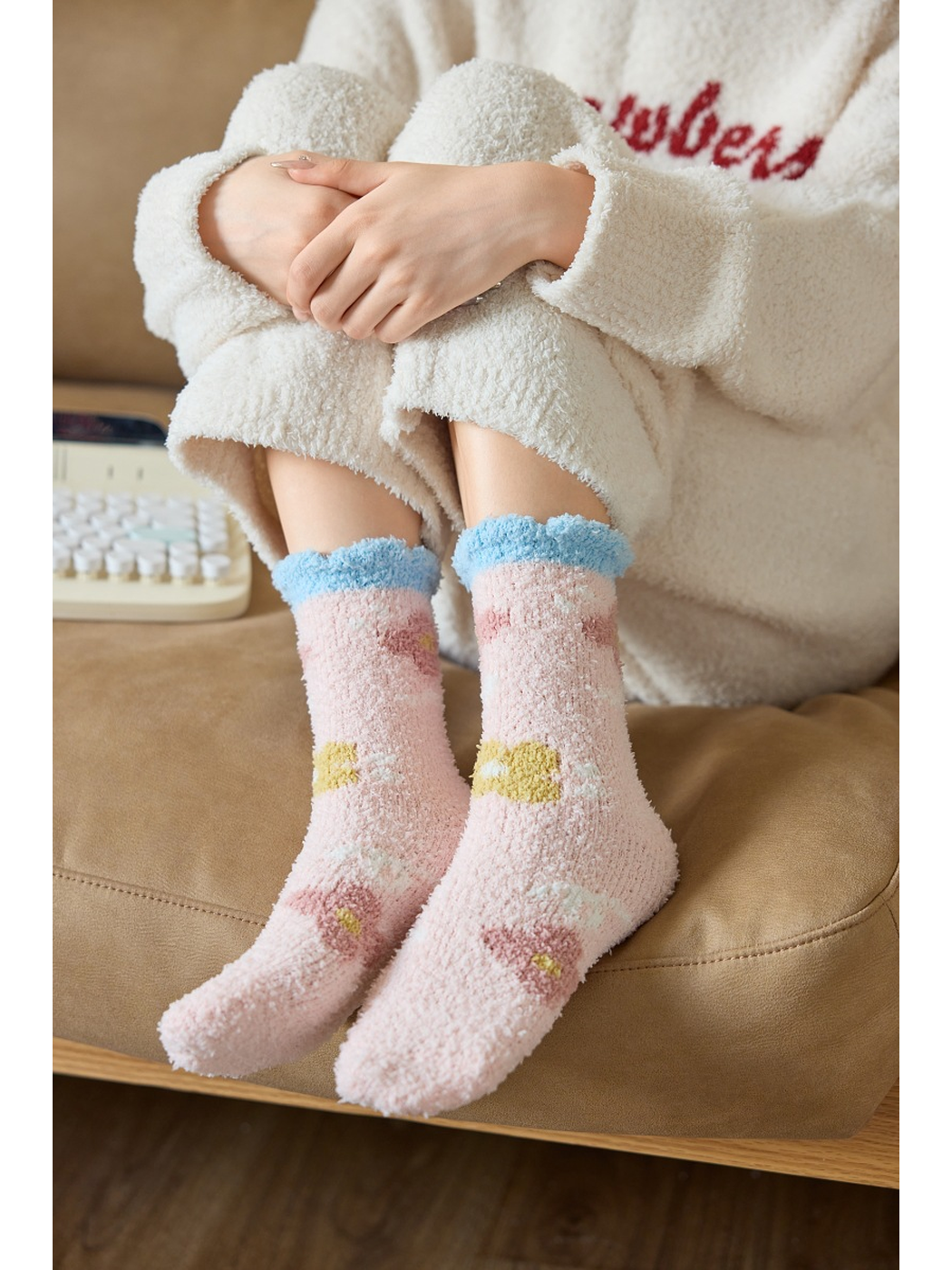 Light pink fuzzy flower-pattern socks worn while seated on a sofa
