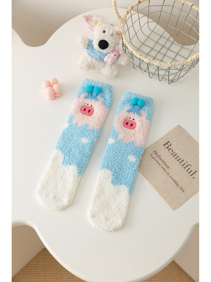 Light blue fuzzy socks with pink pig motif, pom-poms and white toes