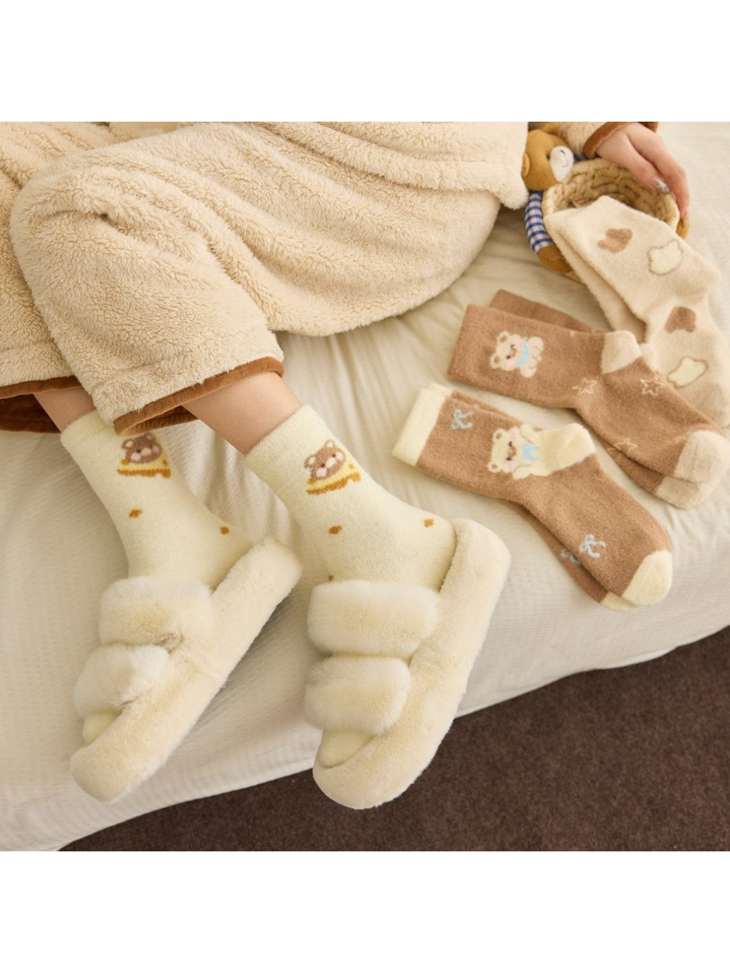Four patterned crew sock styles arranged on a bed with slippers