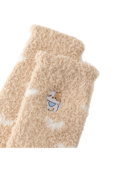 Close-up of beige fuzzy socks with an embroidered cat and white cloud accents