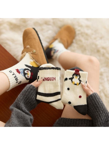 Three penguin sock designs displayed while one pair is worn with slippers