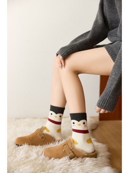 Ivory penguin-face crew socks with dark cuffs and red ankle bands worn with slippers