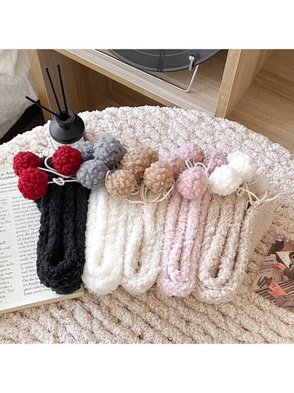 Fuzzy pom-pom socks in five colors displayed with their folded soles