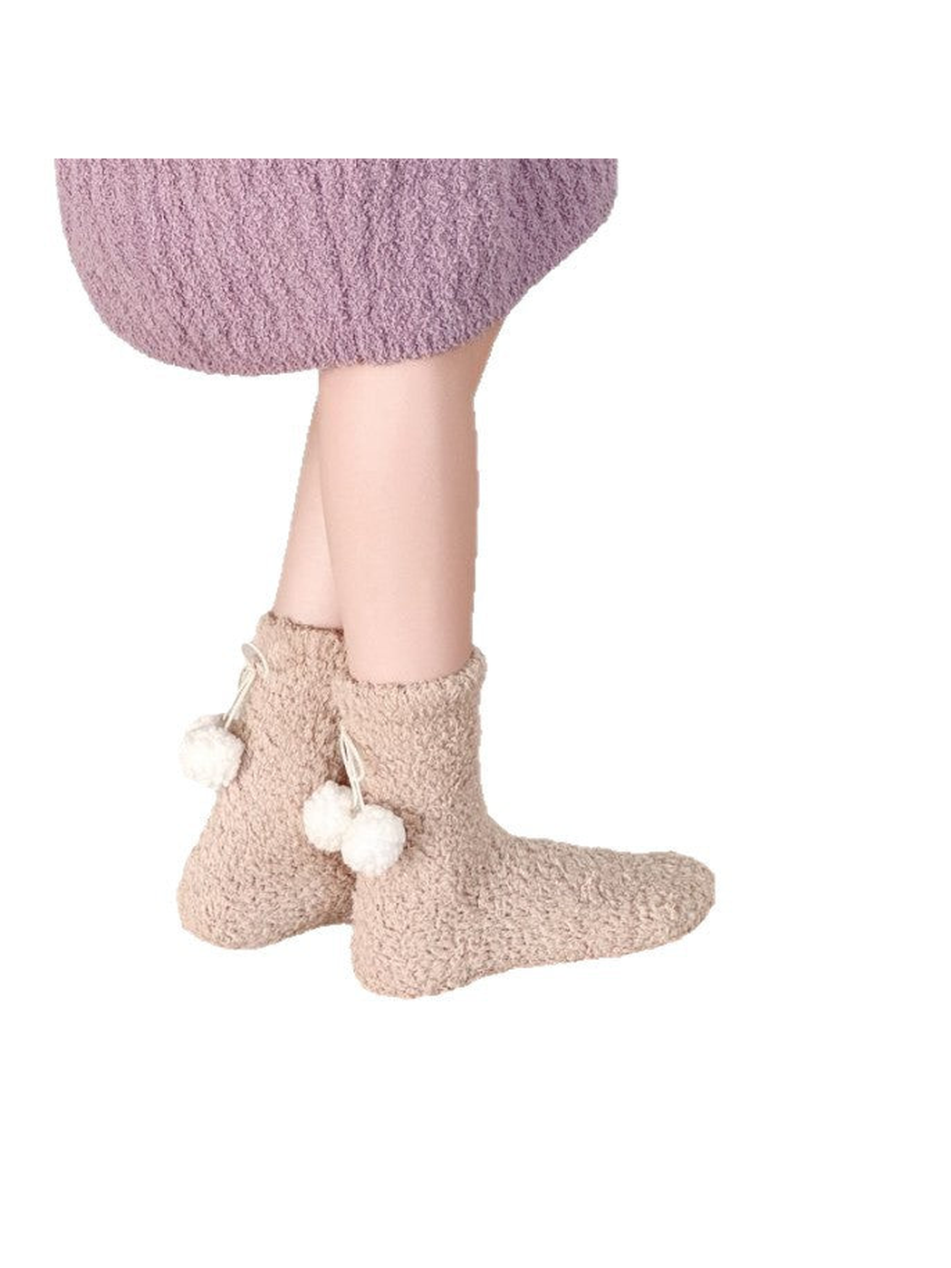 Beige fuzzy socks with white pom-pom ties worn above the ankle