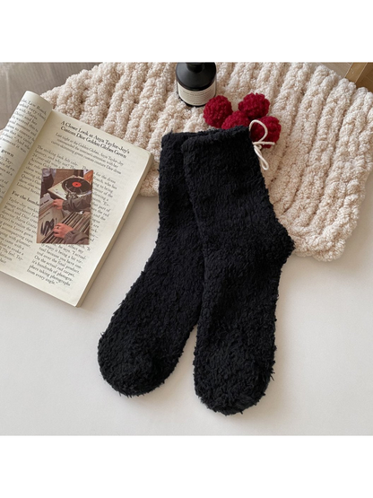 Black fuzzy socks with red pom-pom ties